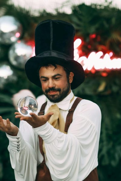Magician demonstrates a captivating crystal ball trick during an enchanting outdoor event.