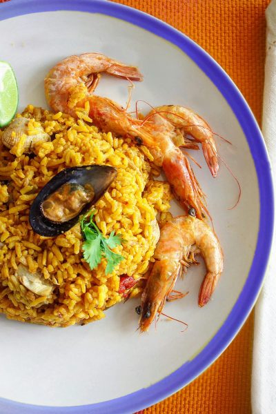 Close-up of a traditional seafood paella with shrimp and lime, perfect for food enthusiasts.